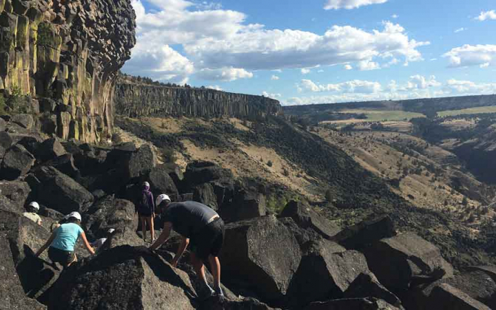 a small group of students navigate large rocks on an outward bound course